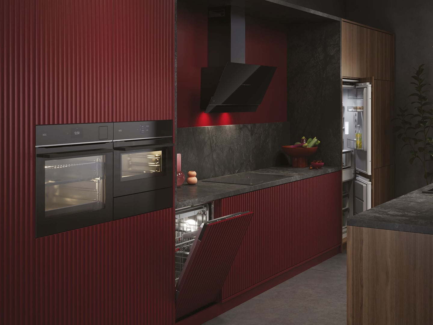 Een bordeaux rode keuken met hierin opgenomen diverse AEG keukenapparatuur zoals een oven, afzuigkap en een vaatwasser.
